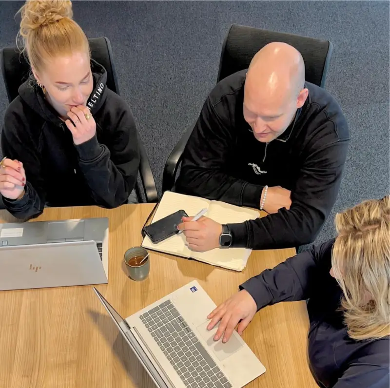 Medewerkers in gesprek met open laptops op tafel